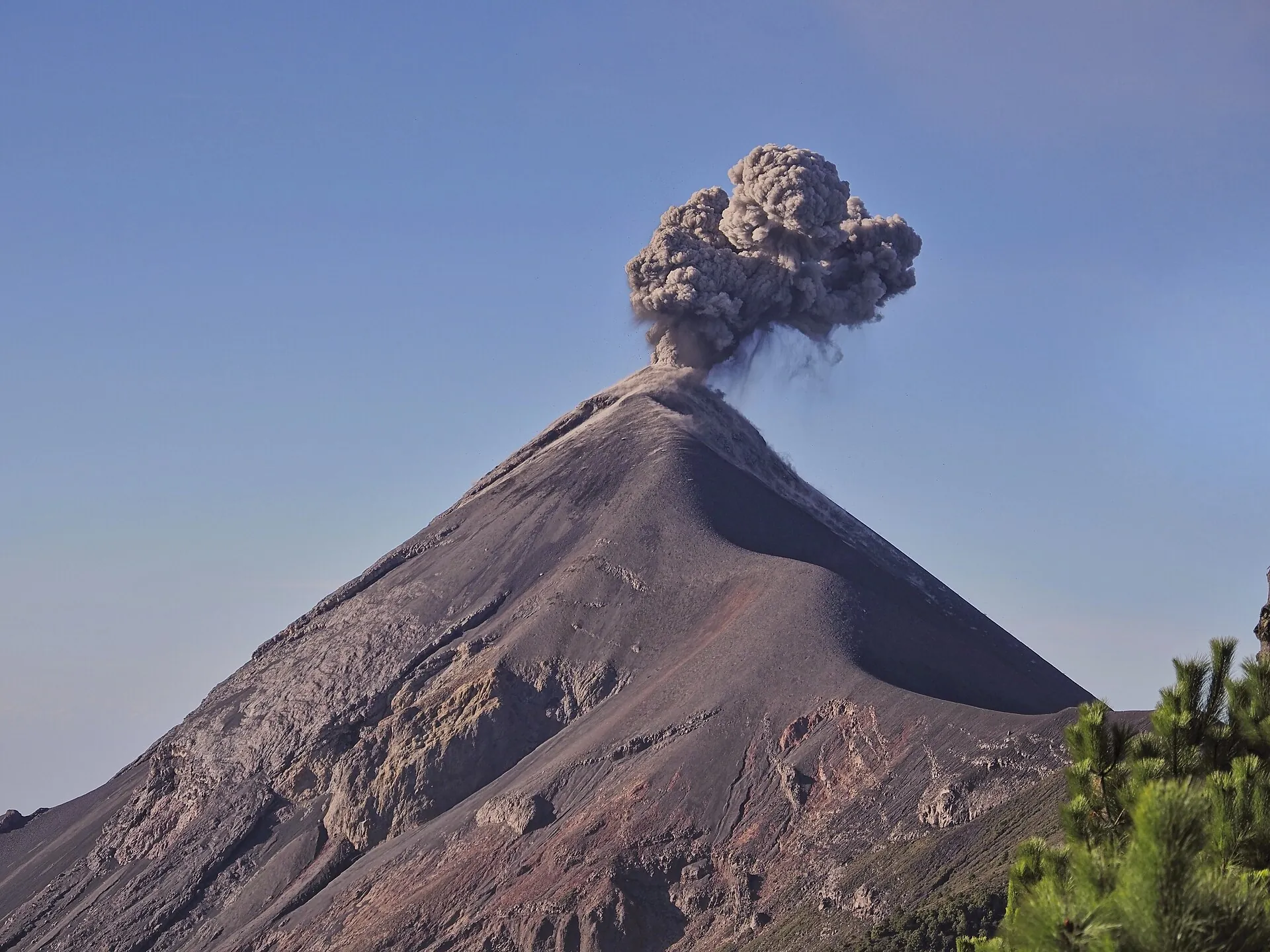 The cone of Volcán de Fuego in morning light, seen from Acatenango: a dark ash cloud rises from the crater