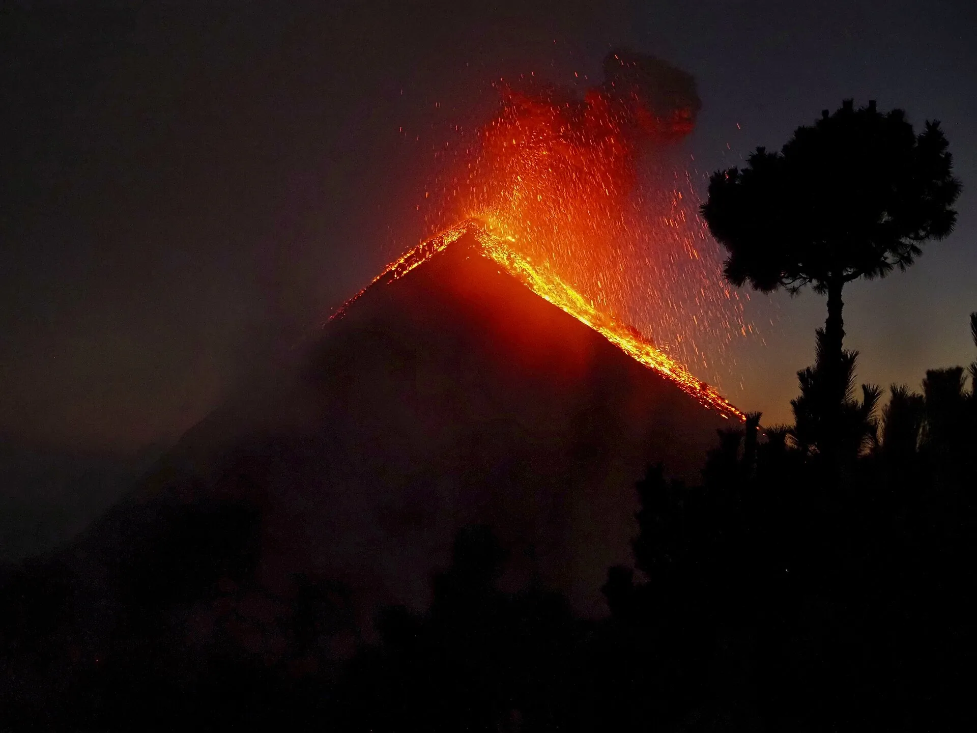 Volcán de Fuego erupting at night, seen from Acatenango: glowing rock flies out of the crater and tumbles down the flank