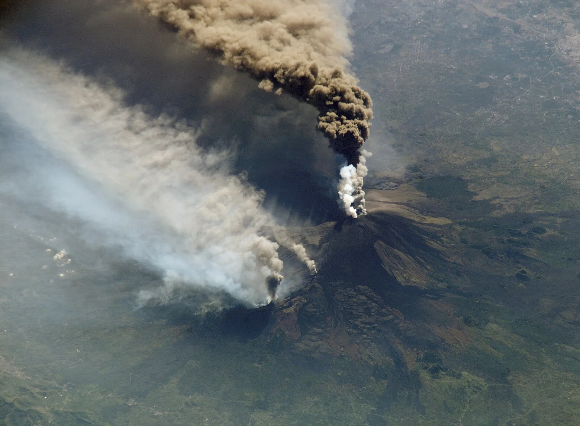 Photograph from the International Space Station on October 30, 2002: the ash column of Mount Etna drifting south, with smoke from fires the lava set on the north flank