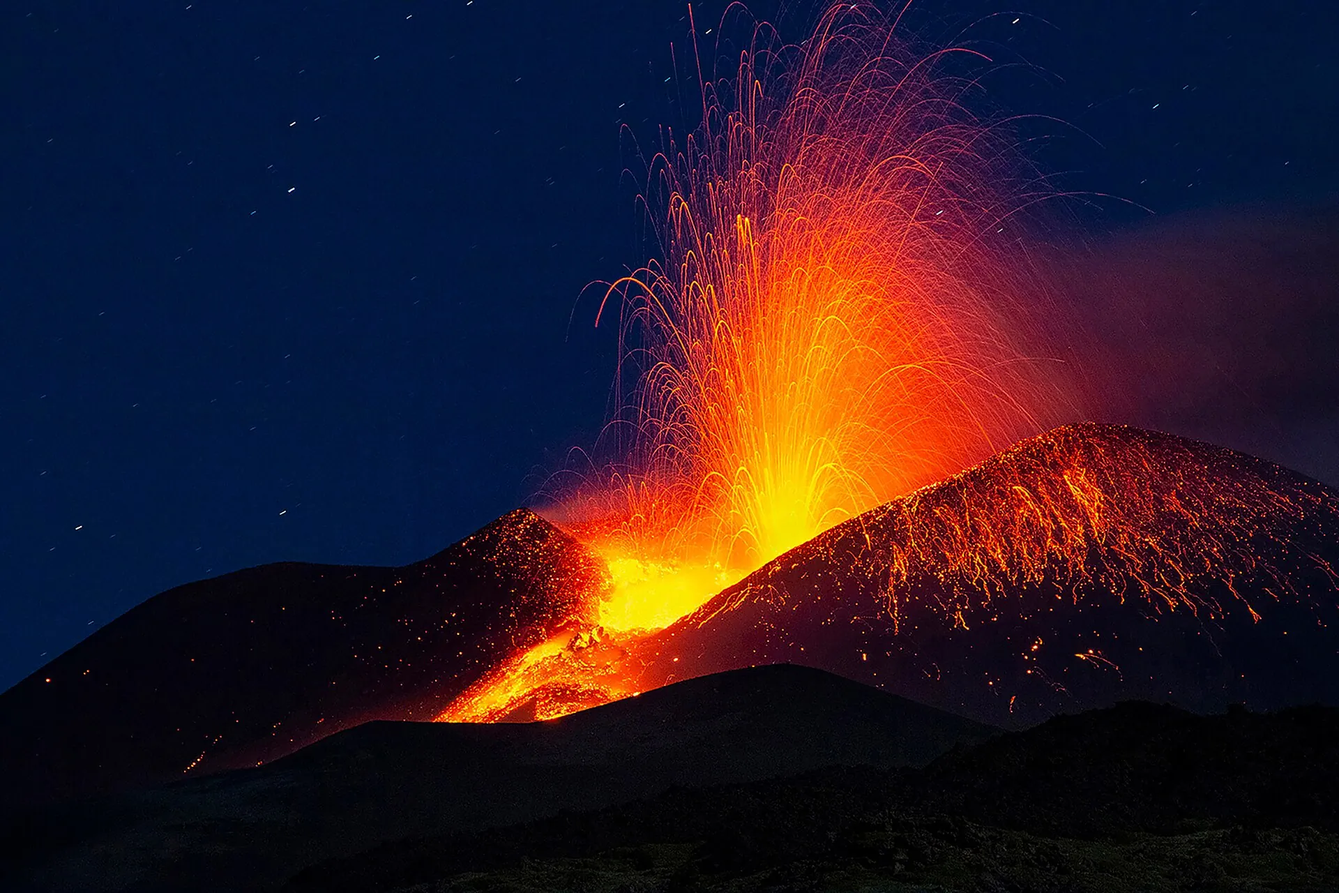 Lavafontäne am Südostkrater des Ätna bei Nacht, glühende Lava läuft die Flanke hinab