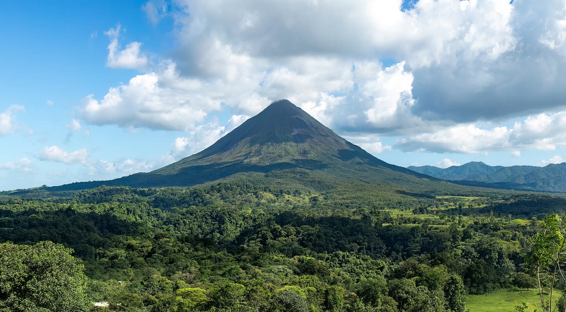 The cloud-free cone of Arenal Volcano above rainforest and pasture, Costa Rica