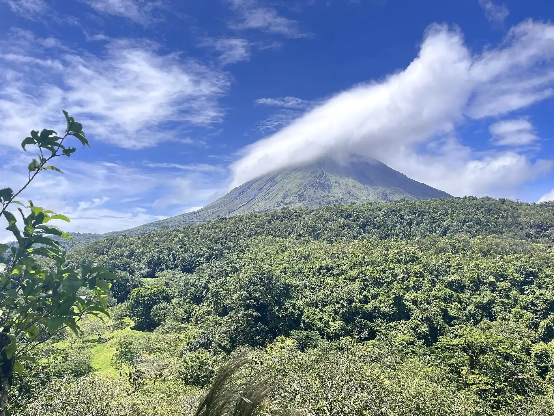 Arenal Volcano rising above the rainforest near La Fortuna, its summit wrapped in a plume of cloud