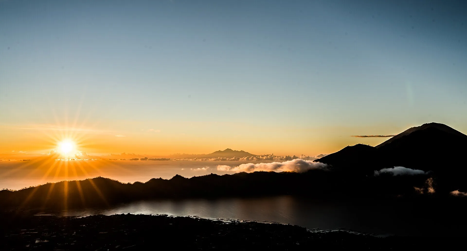 Sunrise from the summit of Mount Batur: the sun above a sea of cloud, Lake Batur below, the cone of Abang on the right