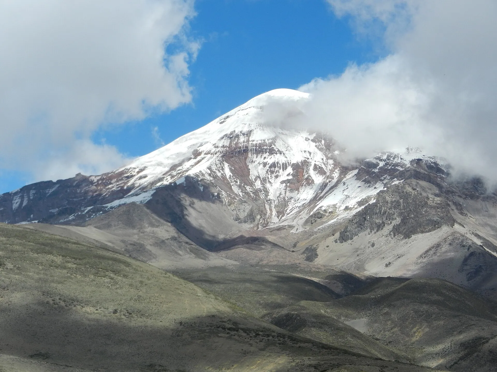 Der Gipfelaufbau des Chimborazo aus der Nähe: Schnee, Eis und dunkle Felsrippen unter Wolken