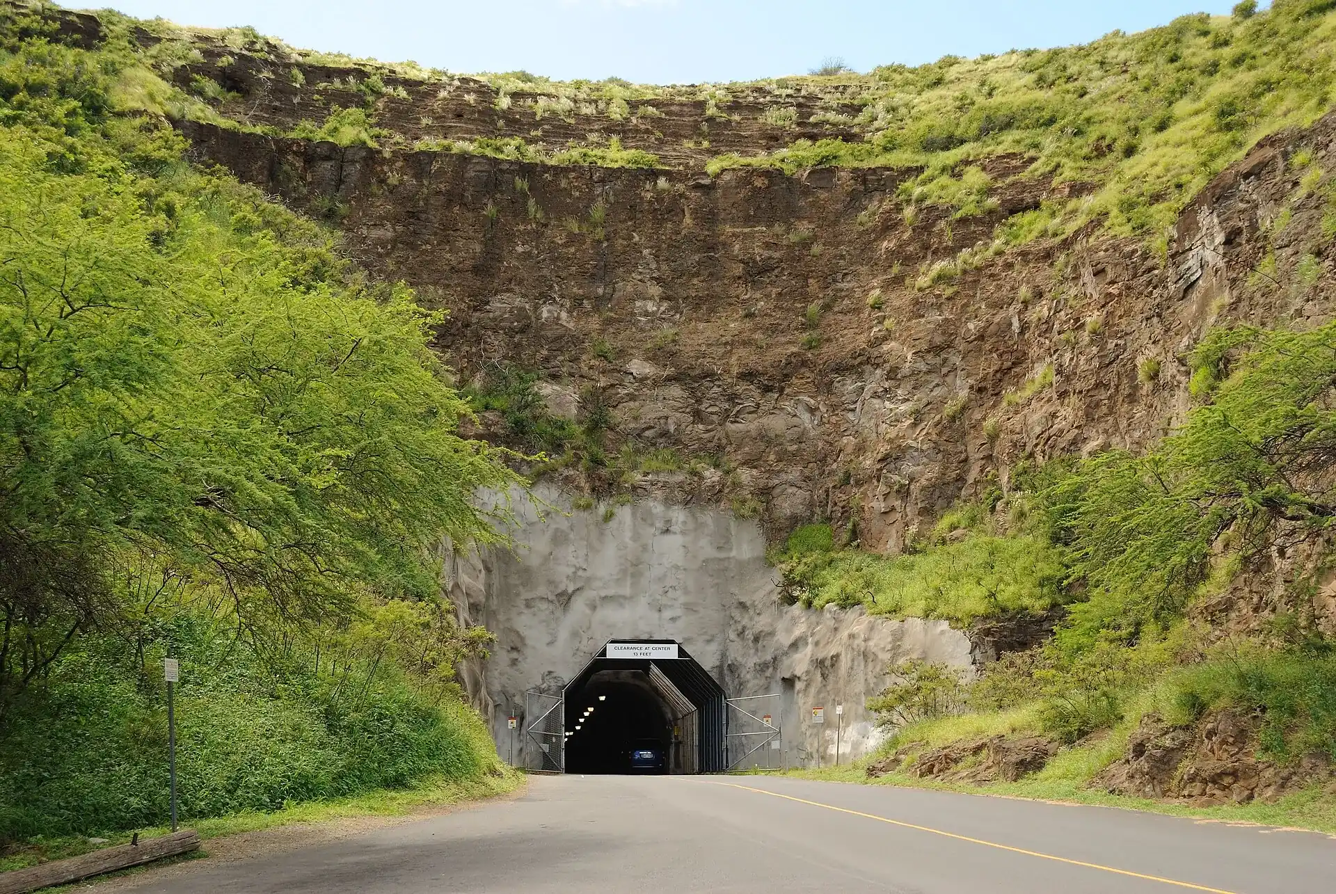 Road to the Diamond Head access tunnel: a dark tunnel portal in the steep brown tuff wall of the crater