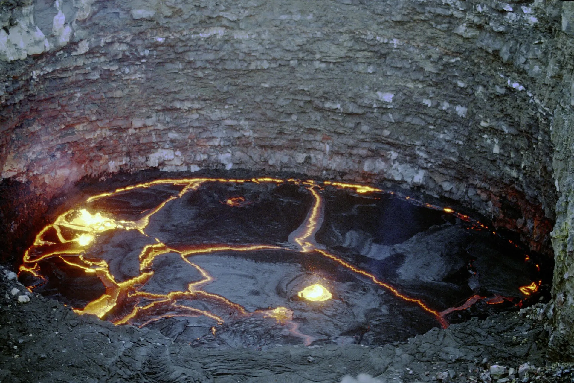 Historic photograph from 2001: looking down into the lava lake of Erta Ale, glowing cracks running across the dark crust