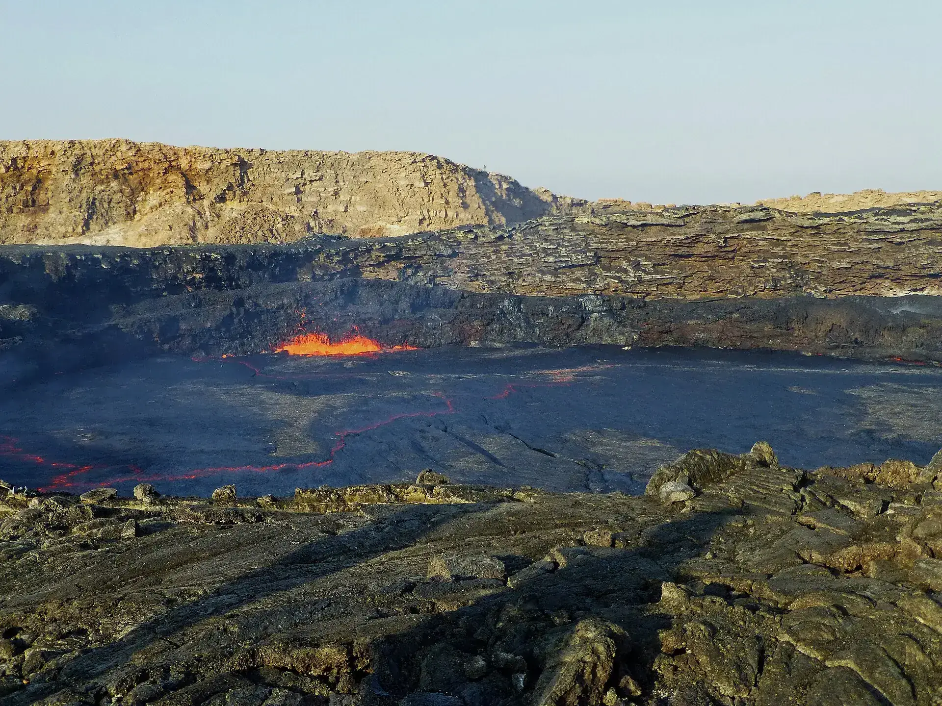 Historic photograph taken before 2025: red lava glows in a fissure at the edge of the dark lava lake inside the crater of Erta Ale