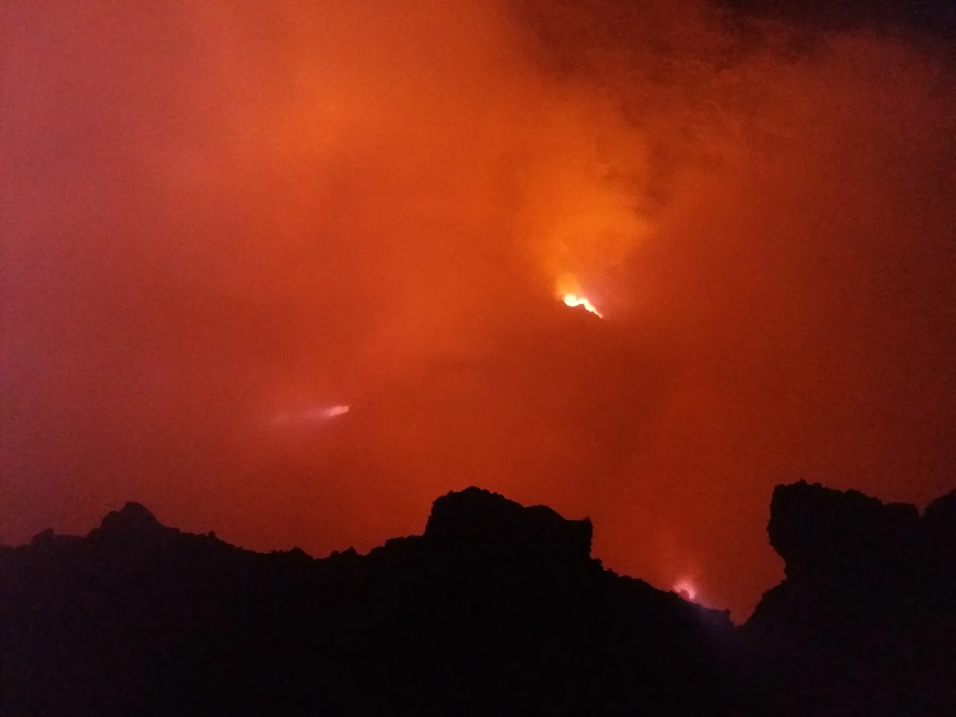 Historic night photograph taken before 2025: red-glowing fume above the crater of Erta Ale, the dark silhouette of the rim in front