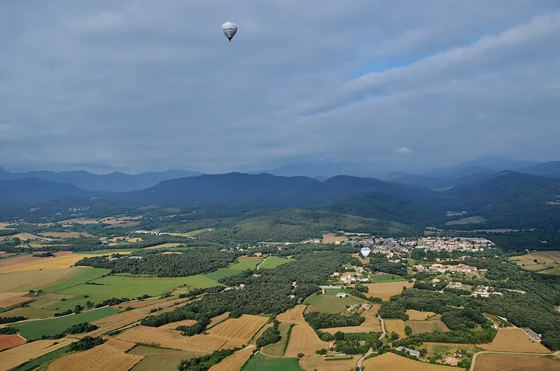 Ein Heißluftballon über der Ebene der Garrotxa, unten Felder und die Kegel der Vulkanzone
