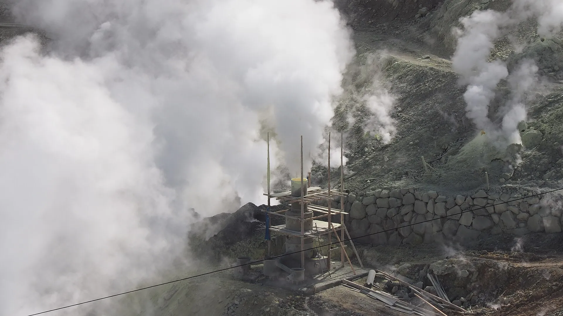 A steam well at Ōwakudani: a thick white column of steam rising next to a wooden scaffold on the gray-yellow slope