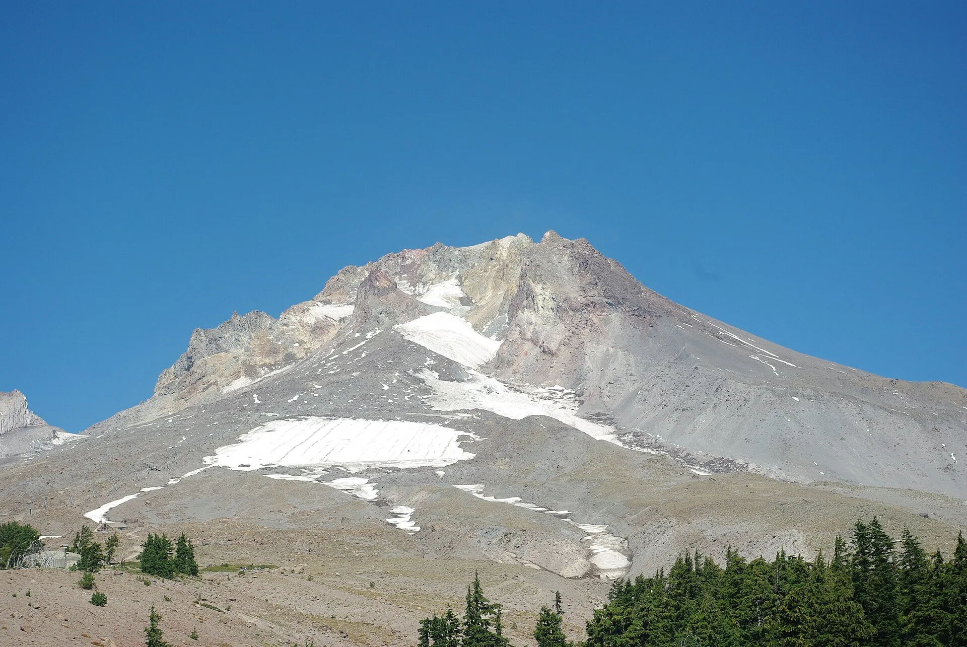 Die Gipfelzone des Mount Hood im Spätsommer: über dem Palmer-Schneefeld liegen nur noch Schneereste, die Flanken sind grau, felsig und von Rinnen durchzogen
