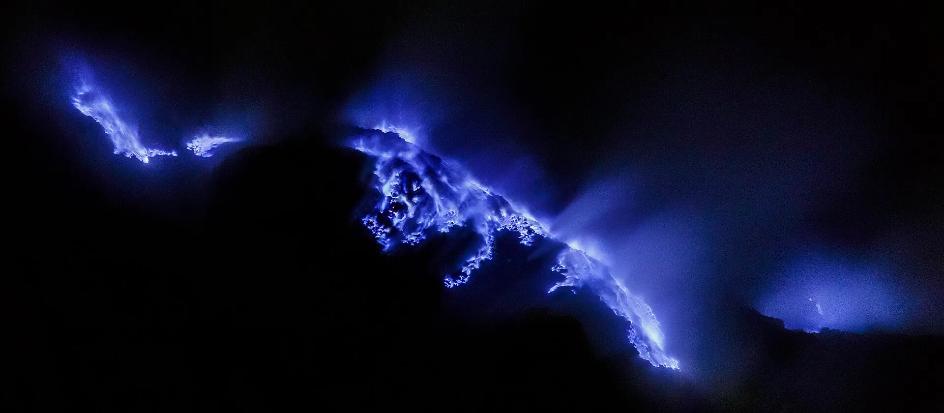 Blue flames from burning sulfur gas in the pitch-black crater of Kawah Ijen