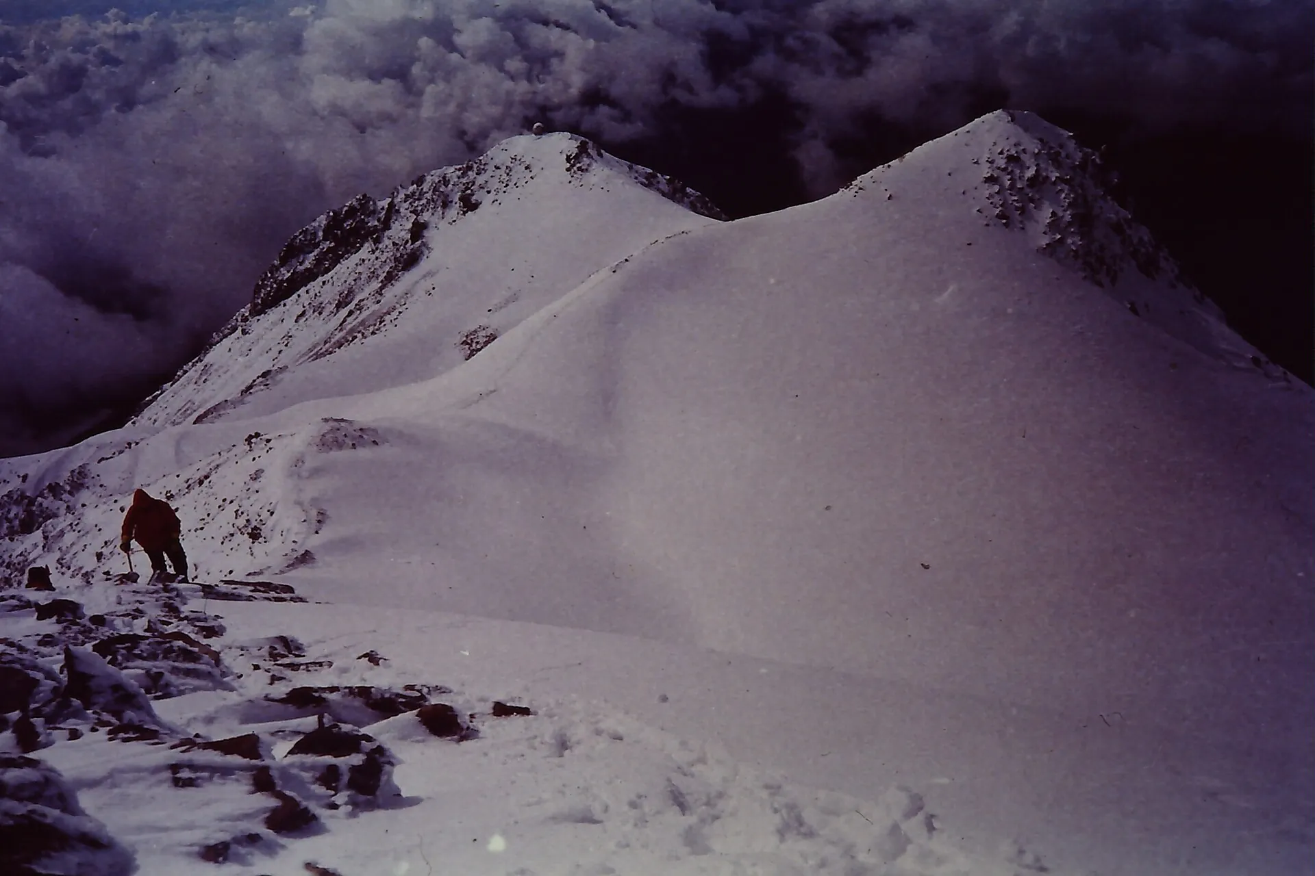 Ein Bergsteiger auf dem verschneiten Gipfelgrat des Iztaccíhuatl, dahinter Wolken