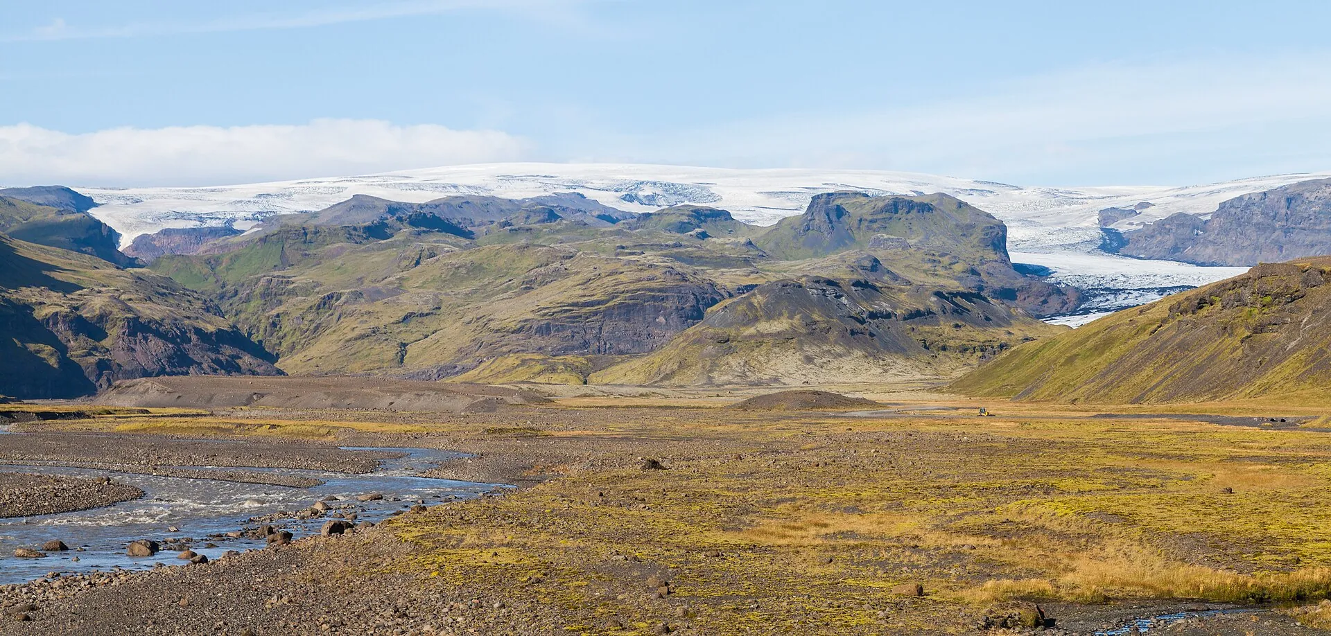 Mýrdalsjökull from the south: a glacier tongue between green mountain slopes, gravel and moss in front