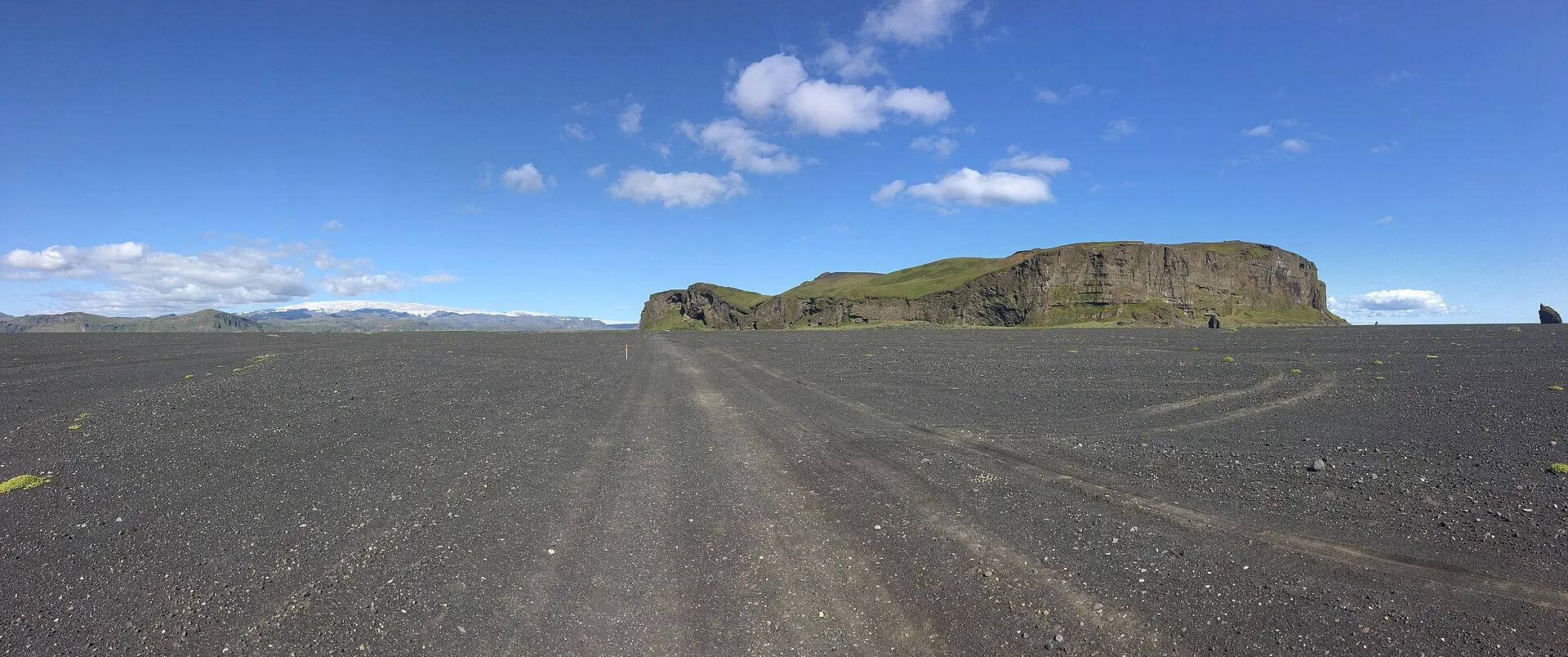 The Mýrdalssandur: a flat black sand plain under a blue sky, with the lone table mountain Hjörleifshöfði