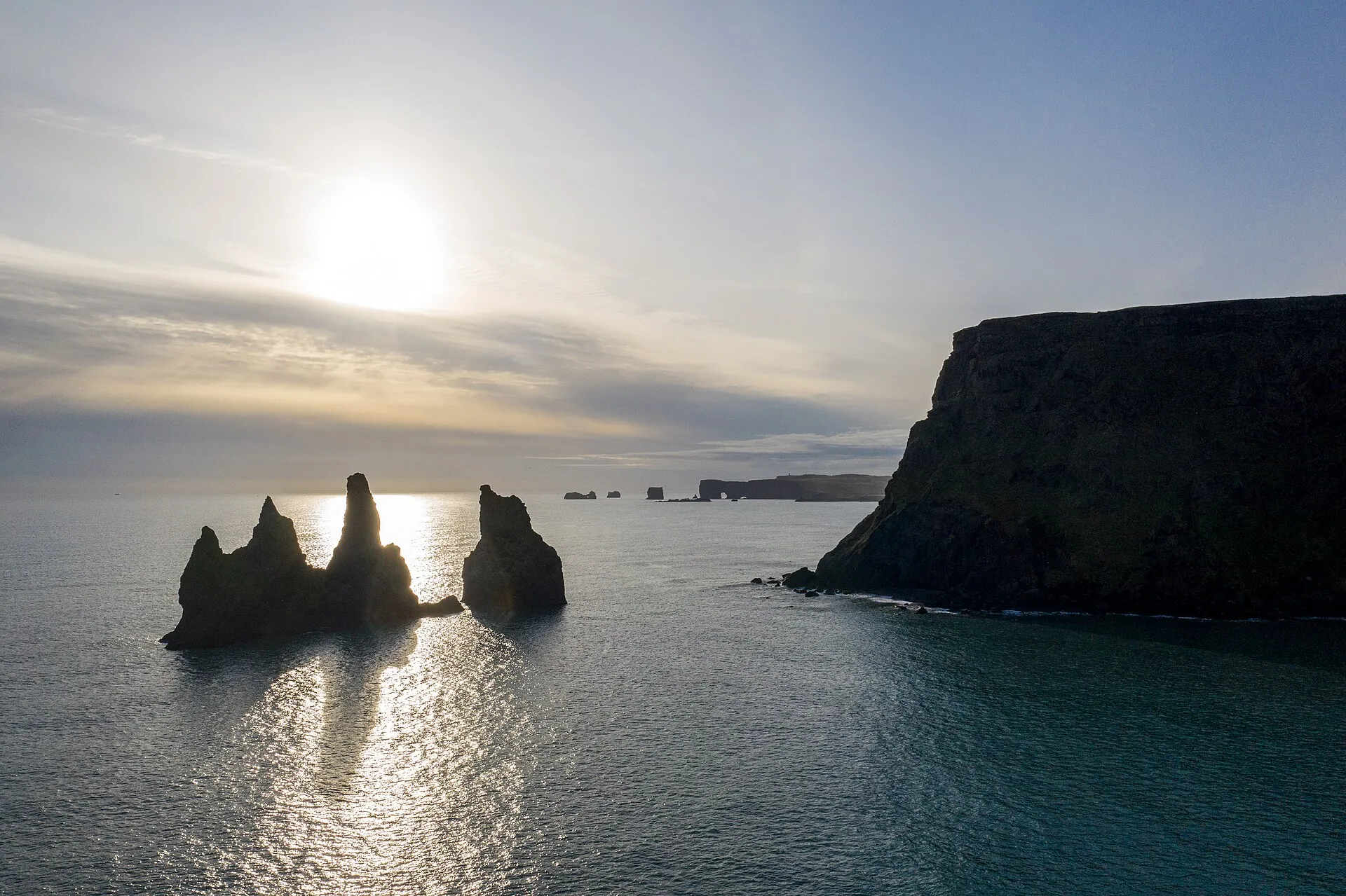 The Reynisdrangar sea stacks off Vík against the low sun, calm sea