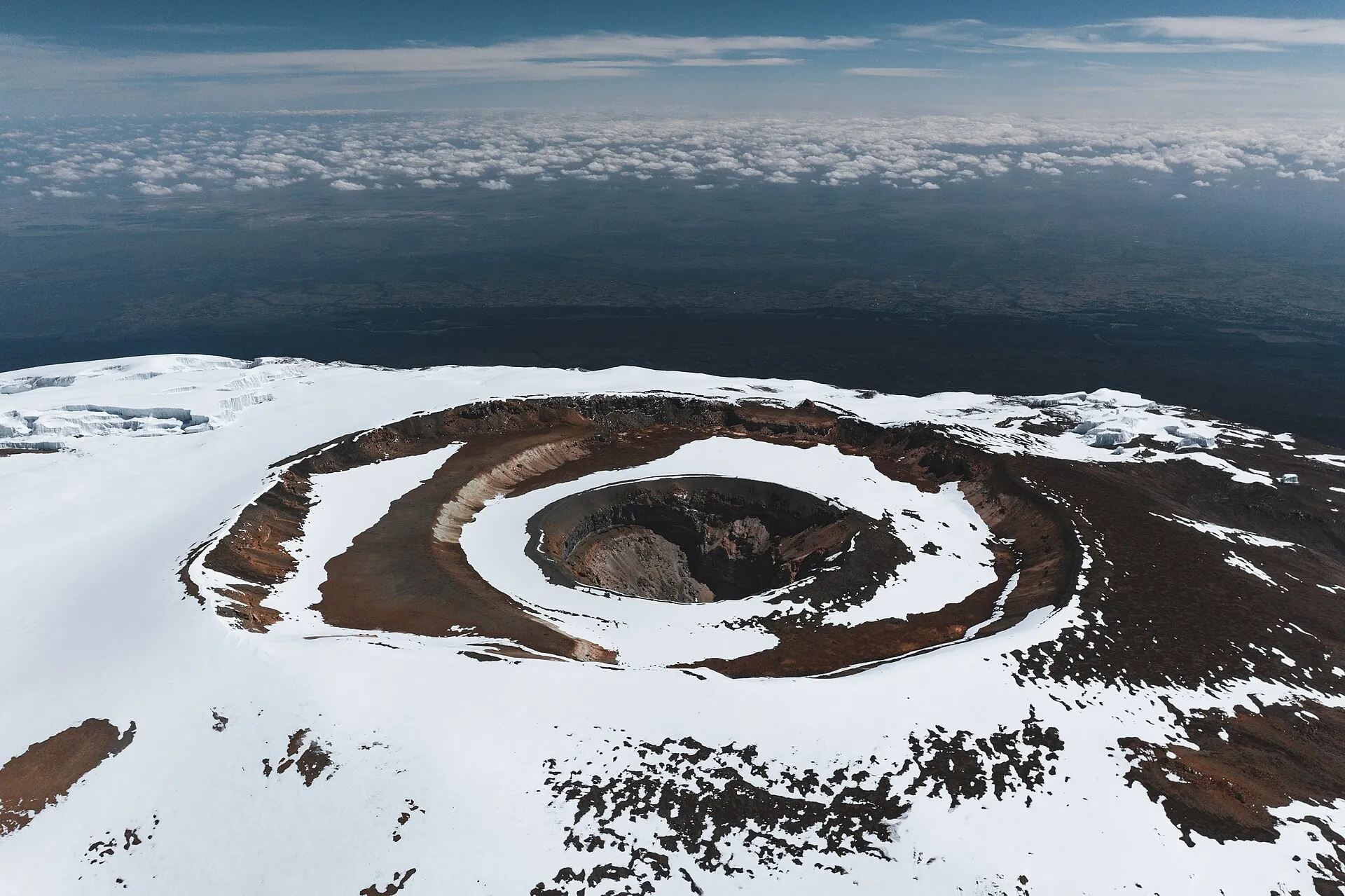 Aerial view of the Kibo summit crater on Kilimanjaro: the inner Reusch Crater in red-brown rock, ringed by snow and remnant glaciers
