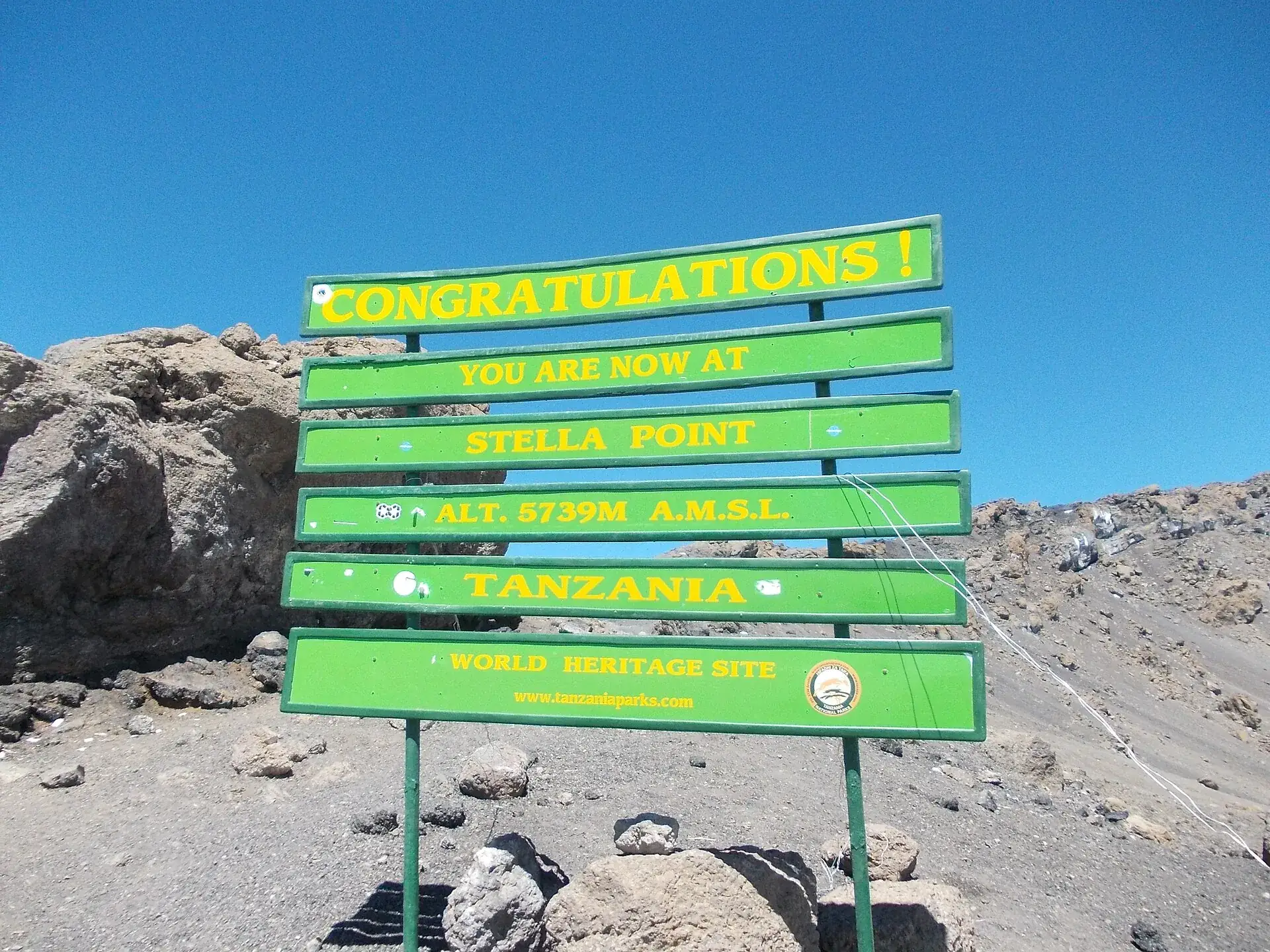 The green sign at Stella Point on Kilimanjaro at 5,739 meters: 'Congratulations, you are now at Stella Point'