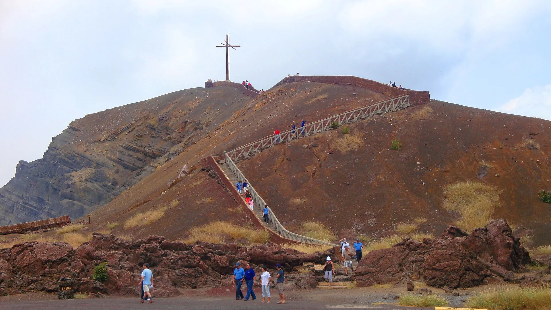 Besucher steigen die Treppe zum Kreuz von Bobadilla auf dem rotbraunen Kraterrand des Masaya hinauf