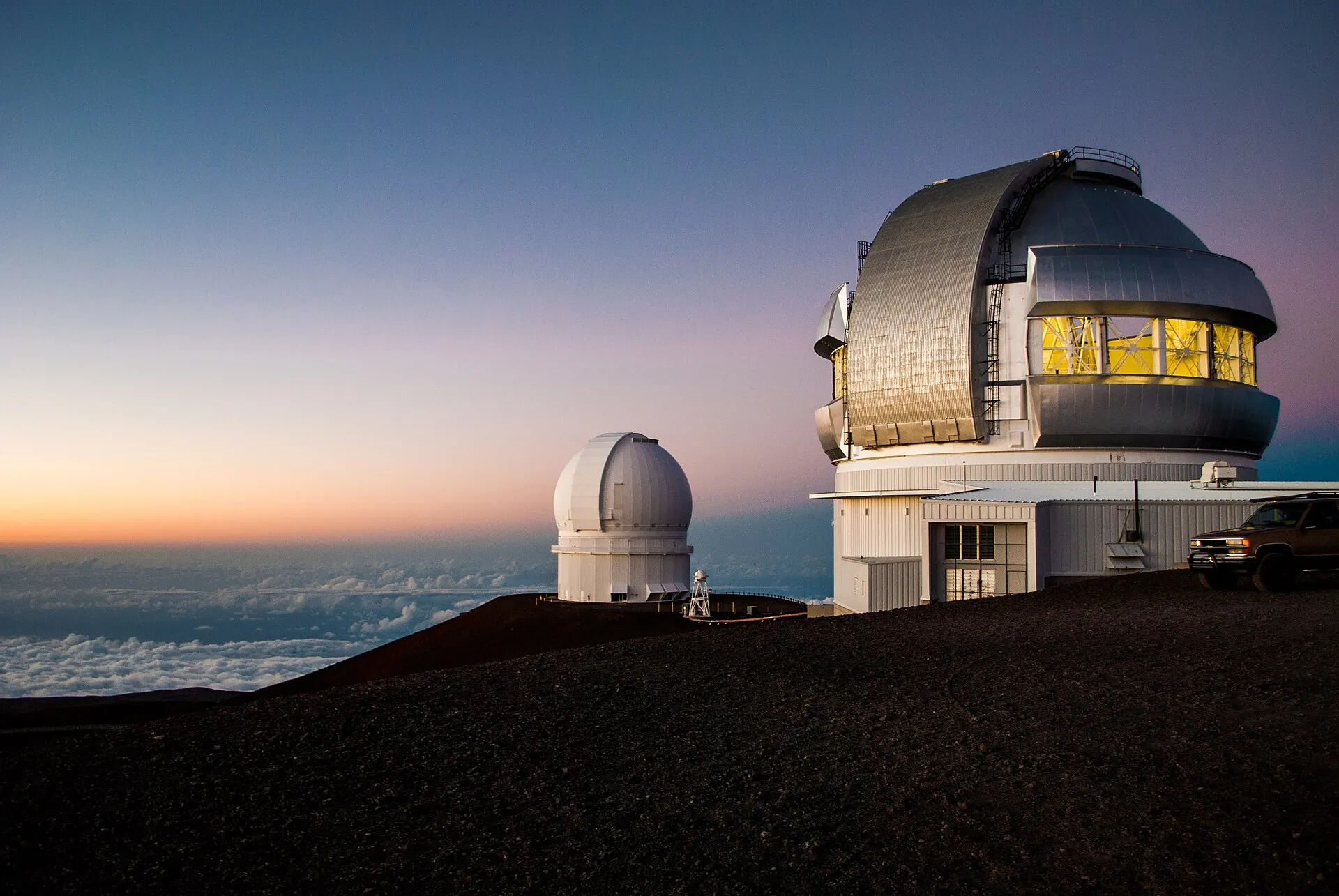 Observatories on the summit of Mauna Kea in the last evening light, with the cloud deck behind the domes