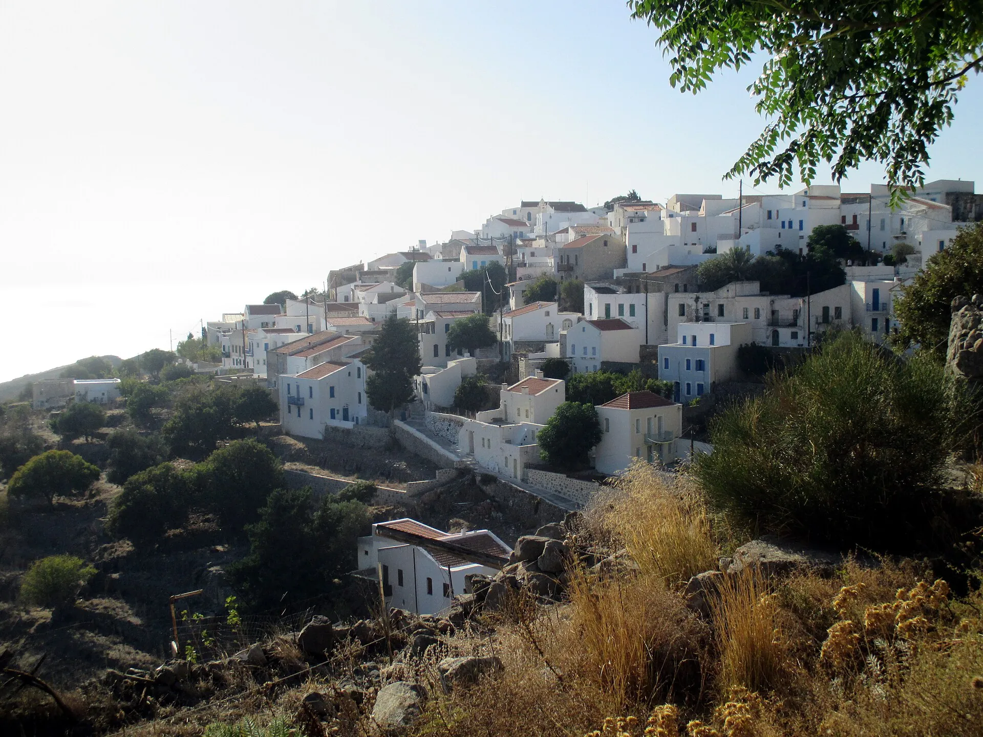 Die weißen Häuser von Nikia am Calderarand von Nisyros im Abendlicht, dahinter das Meer