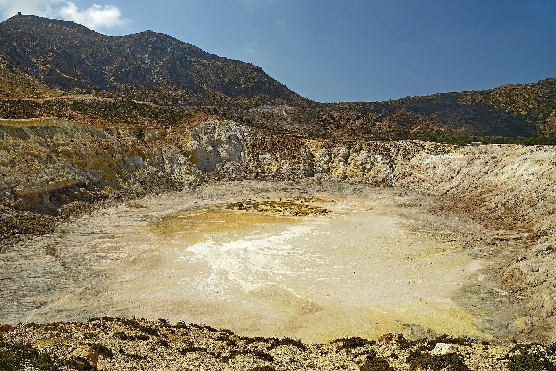 Der Stefanos-Krater auf Nisyros vom Nordostrand aus: heller, ebener Kraterboden mit gelben Schwefelflecken, rundum steile Wände