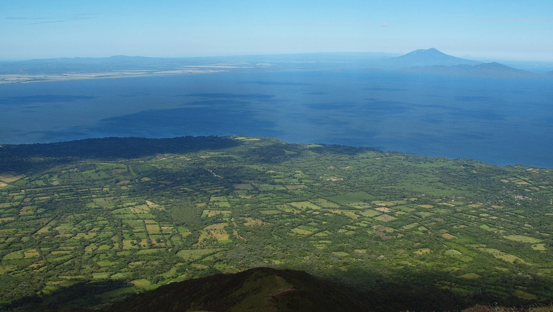 Blick vom Concepción hinunter auf Felder, Wald und das Ufer der Insel Ometepe, dahinter der weite Nicaraguasee