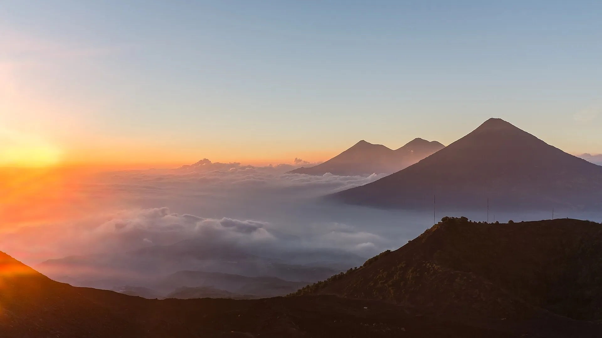 View west from Pacaya at sunset: the volcanoes Agua, Fuego and Acatenango rise out of a sea of clouds