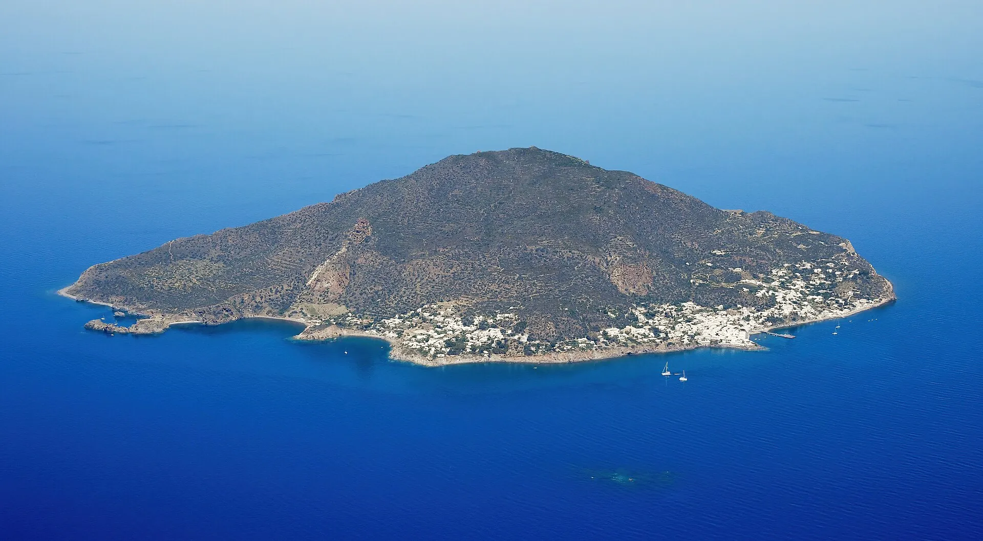 Aerial view of Panarea from the south-east: the flat island with white houses on the east coast in the deep blue sea