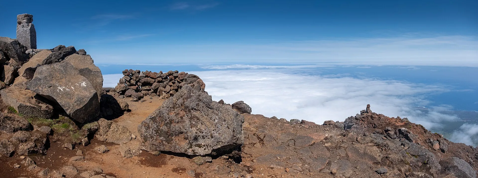 Auf dem Gipfel des Pico: Steinmännchen und Lavablöcke, dahinter das Wolkenmeer über dem Atlantik