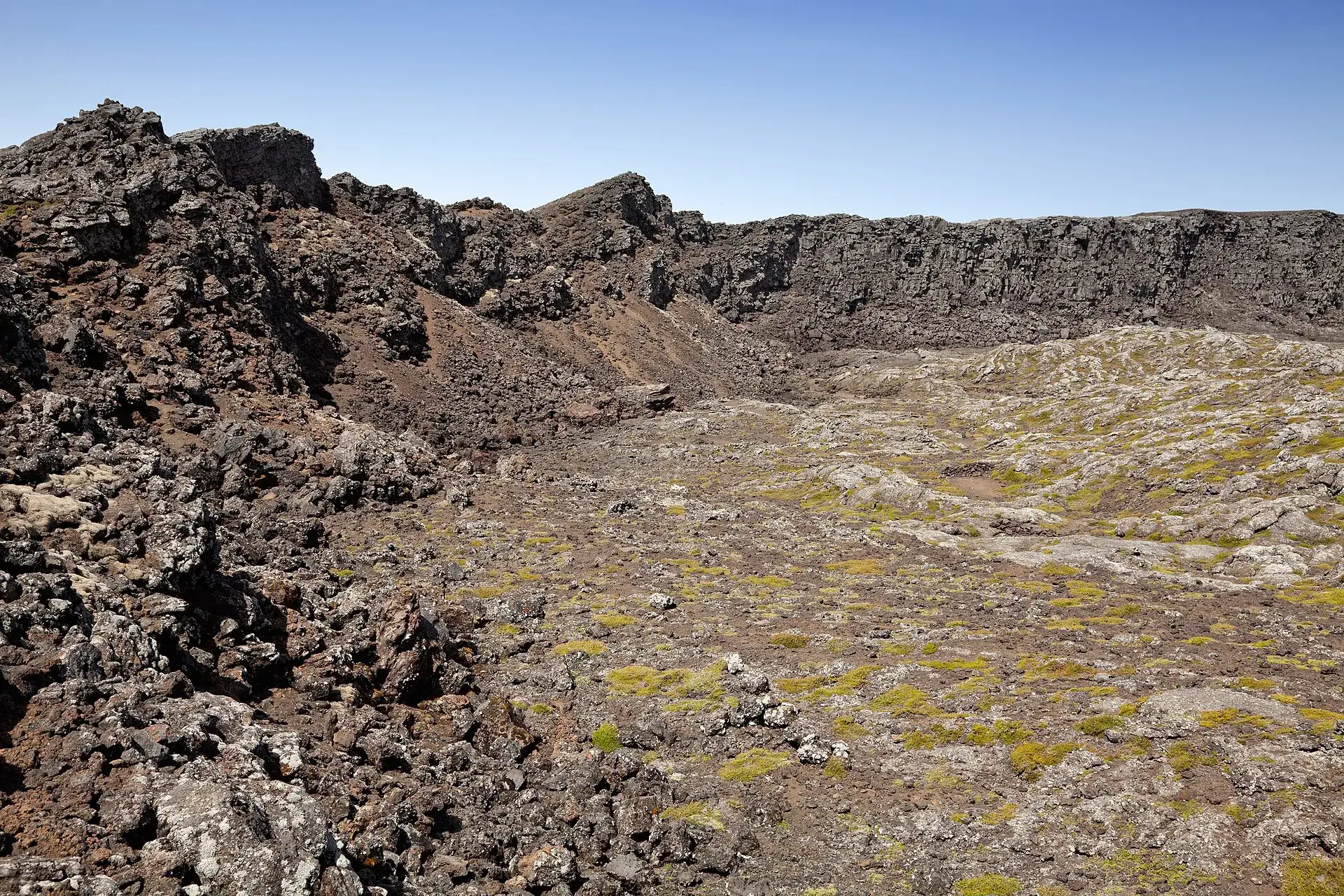 Der Gipfelkrater des Pico: dunkle Lavawälle umschließen den flachen Kraterboden, am Rand steht der Piquinho