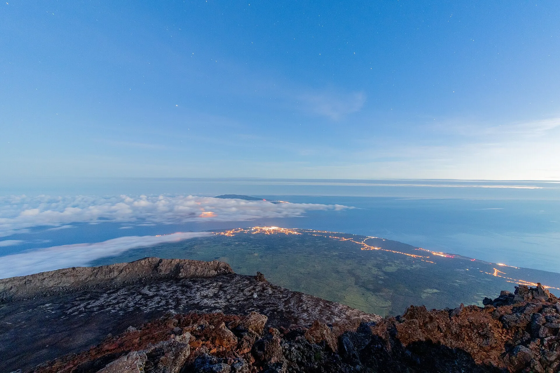 Sonnenaufgang vom Gipfel des Pico: unter der Wolkendecke leuchten die Lichter von Madalena, dahinter die Insel Faial