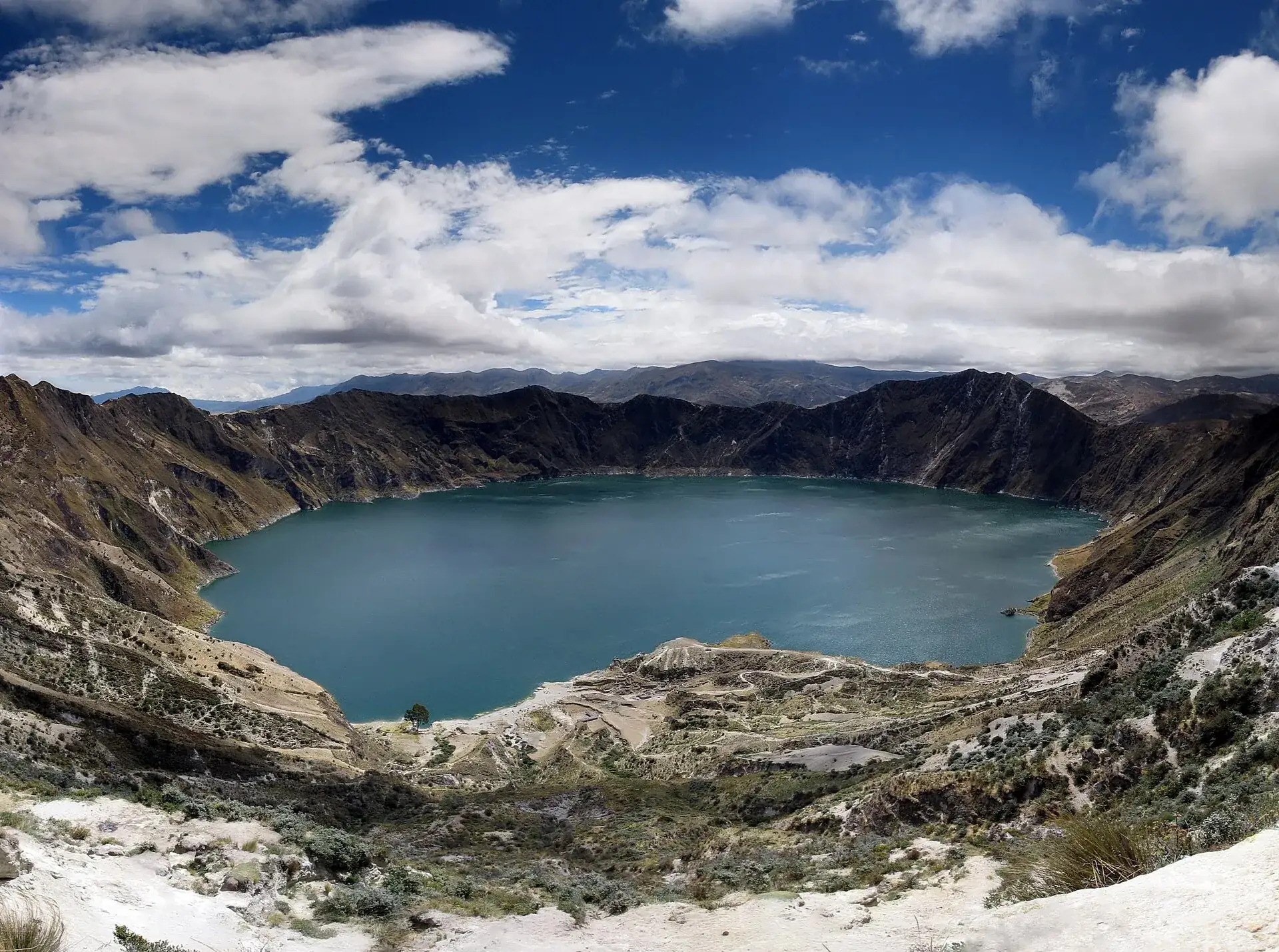 View from the Quilotoa crater rim onto the turquoise crater lake, enclosed by steep brown walls