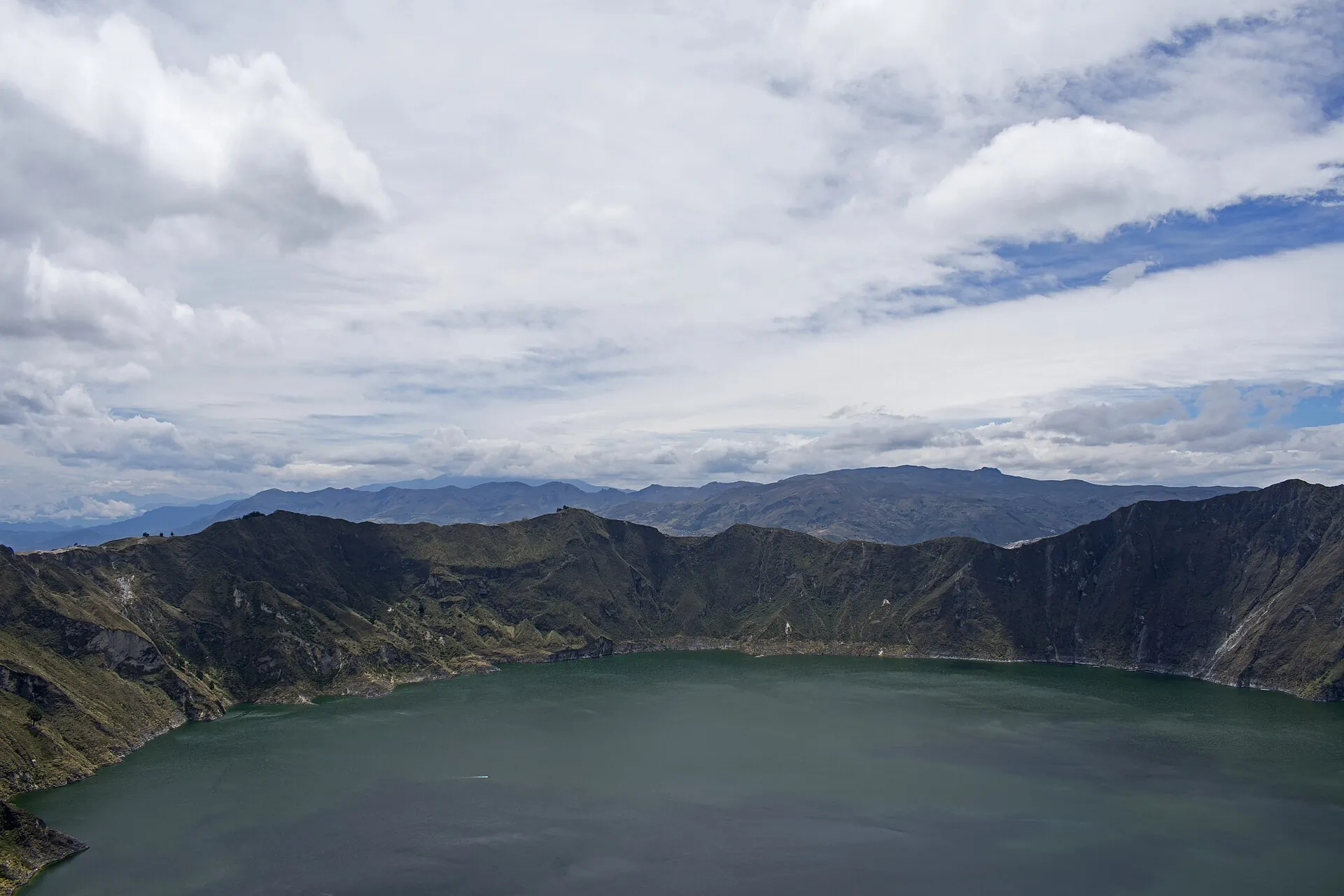 Laguna Quilotoa from Mirador Cristal: the entire crater lake under clouds, the crater walls all around