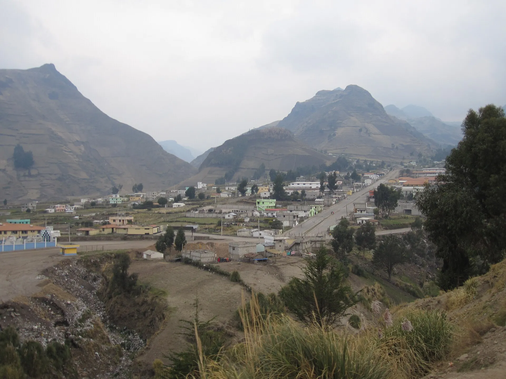 The Andean village of Zumbahua in a high valley, houses and fields, brown mountain slopes behind