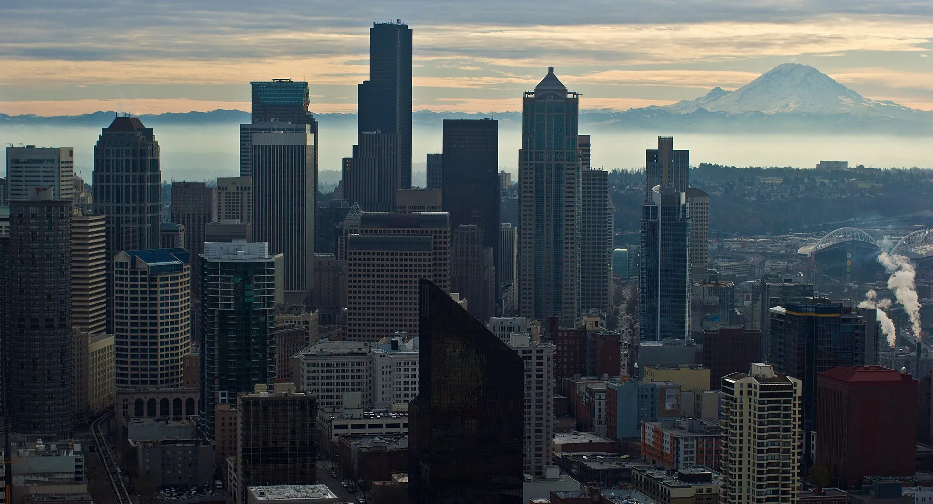 Mount Rainier im Morgenlicht hinter der Skyline von Seattle: die schneebedeckte Vulkankuppe steht über den Hochhäusern der Innenstadt