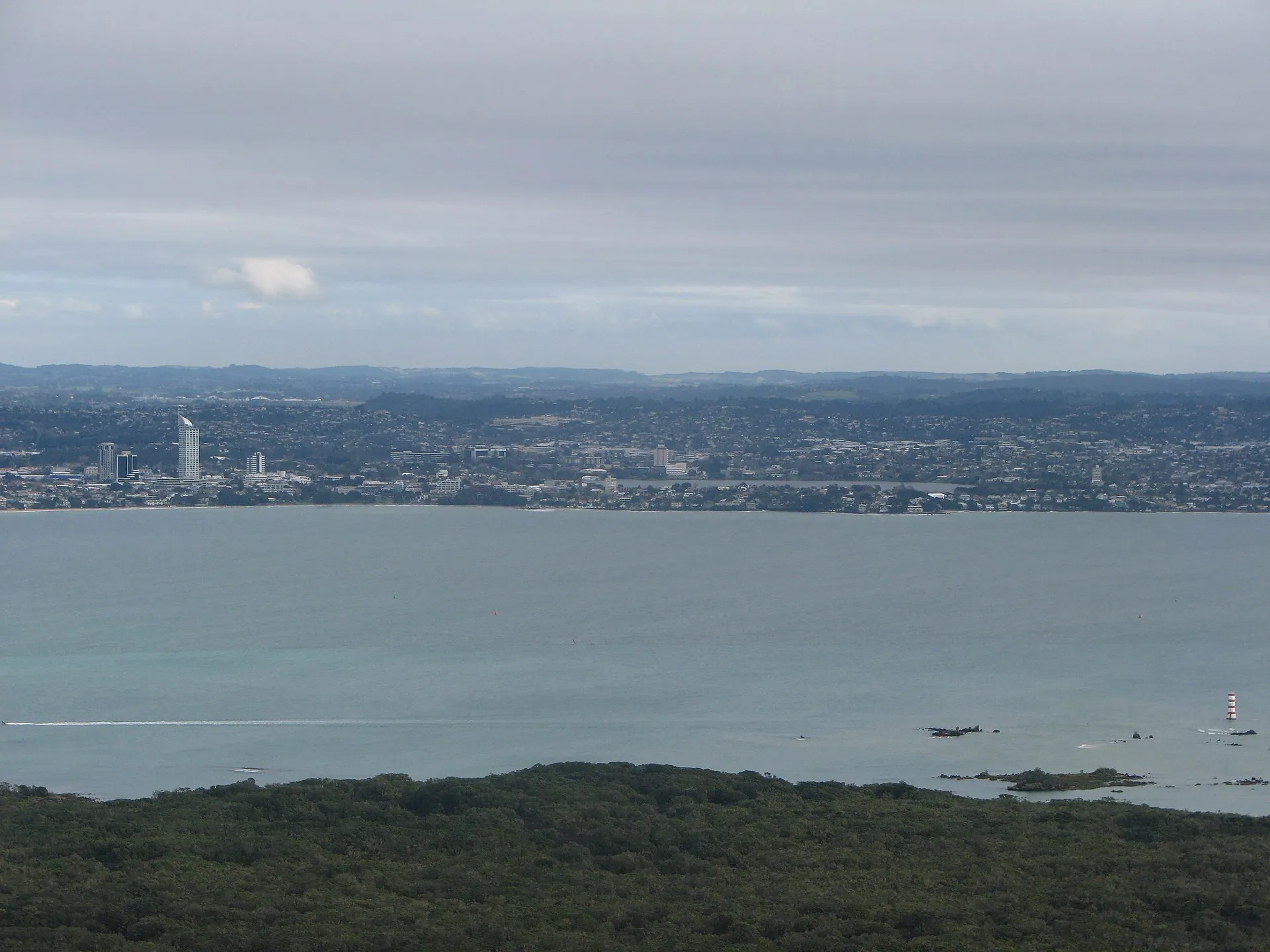 The view from the summit of Rangitoto across the Hauraki Gulf to the Auckland mainland, with the island's pōhutukawa forest in the foreground