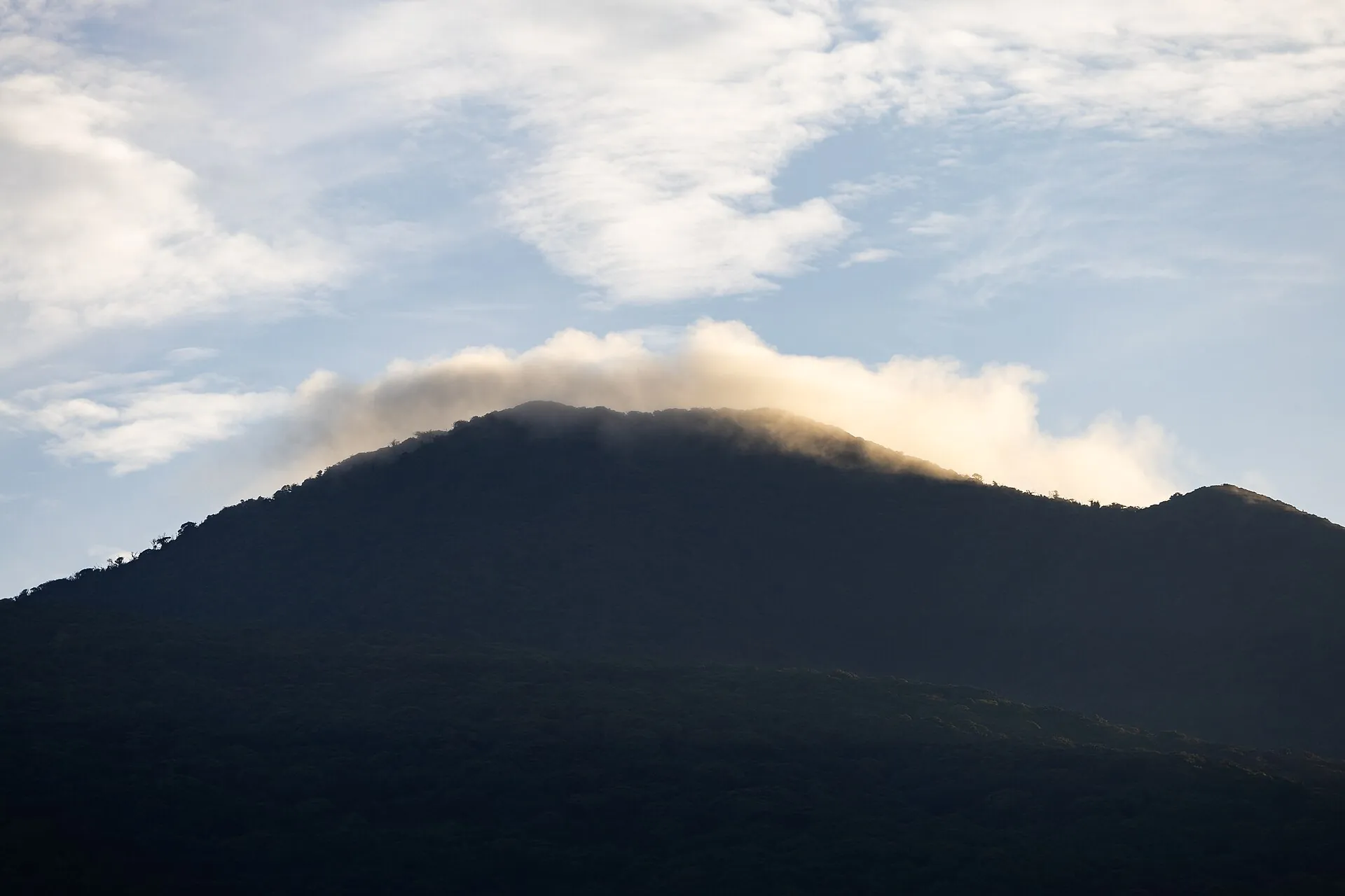 The summit of Rincón de la Vieja as a dark silhouette, clouds gathering over the crater