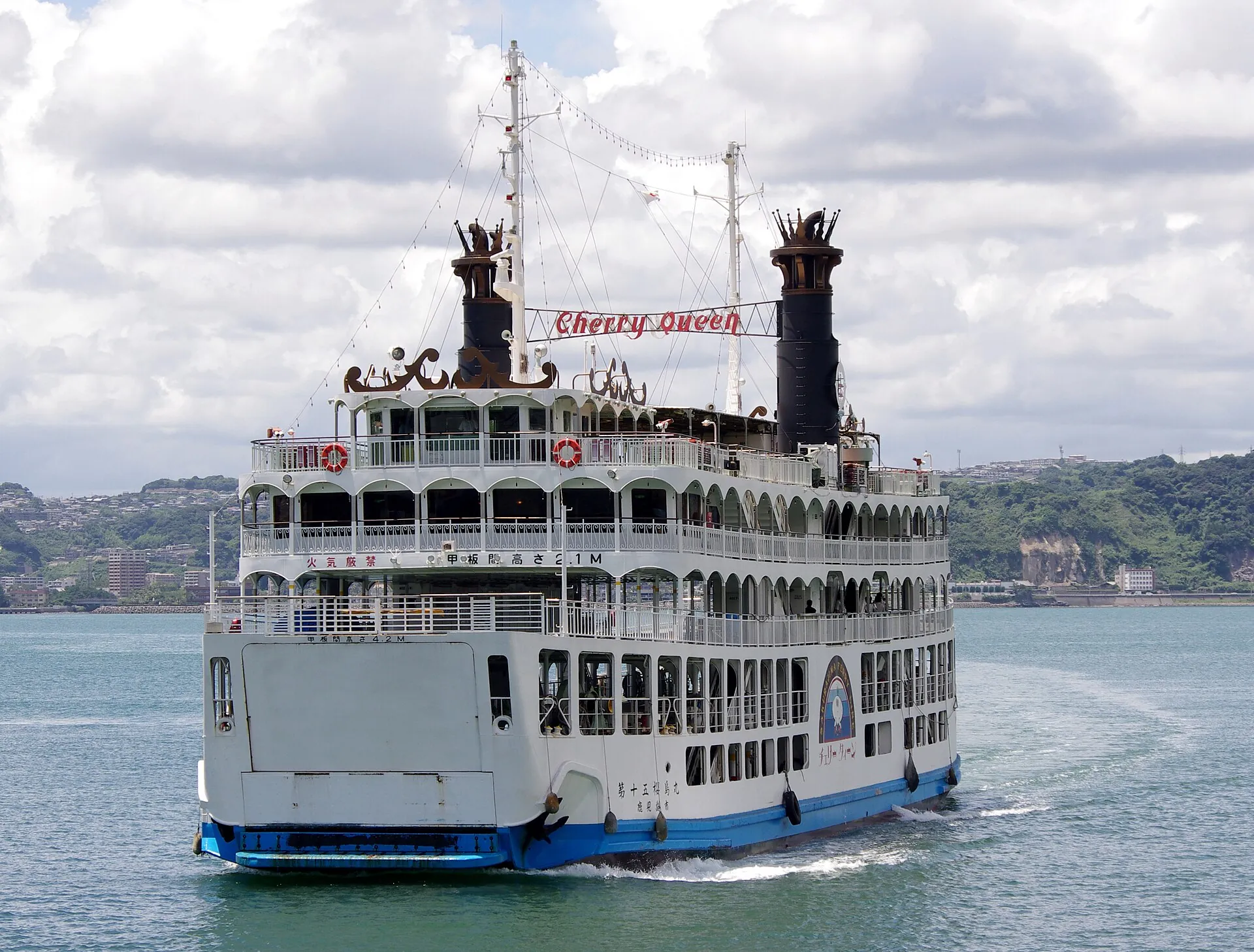 A white multi-deck ferry of the city of Kagoshima with two funnels crossing Kinko Bay