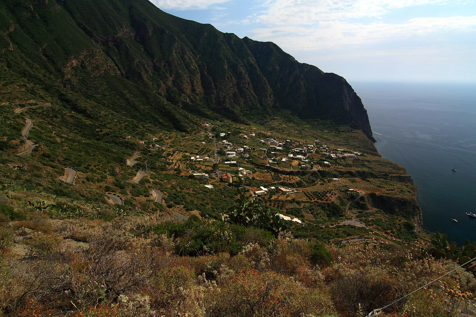 The Pollara caldera on Salina: a semicircular green basin open to the sea, with a few houses on the slope