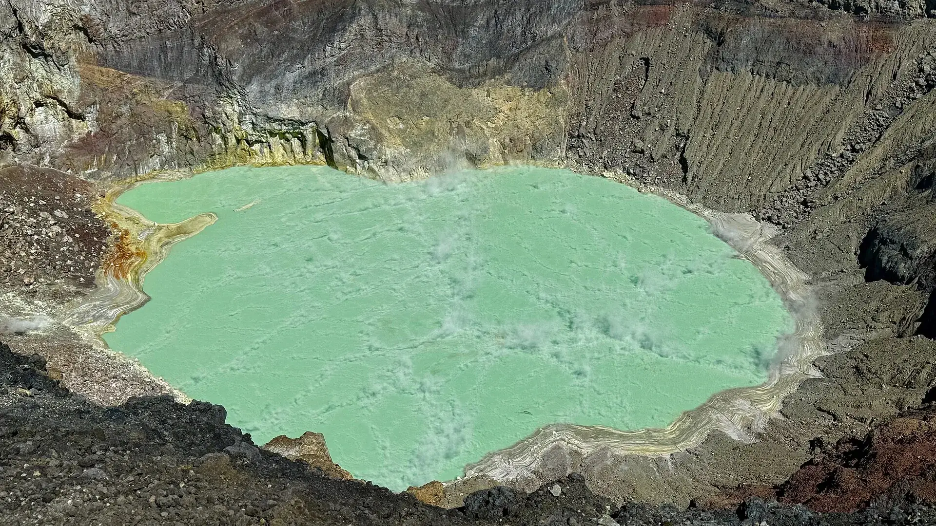 The turquoise-green crater lake of Santa Ana Volcano from above, ringed by gray and yellow crater walls