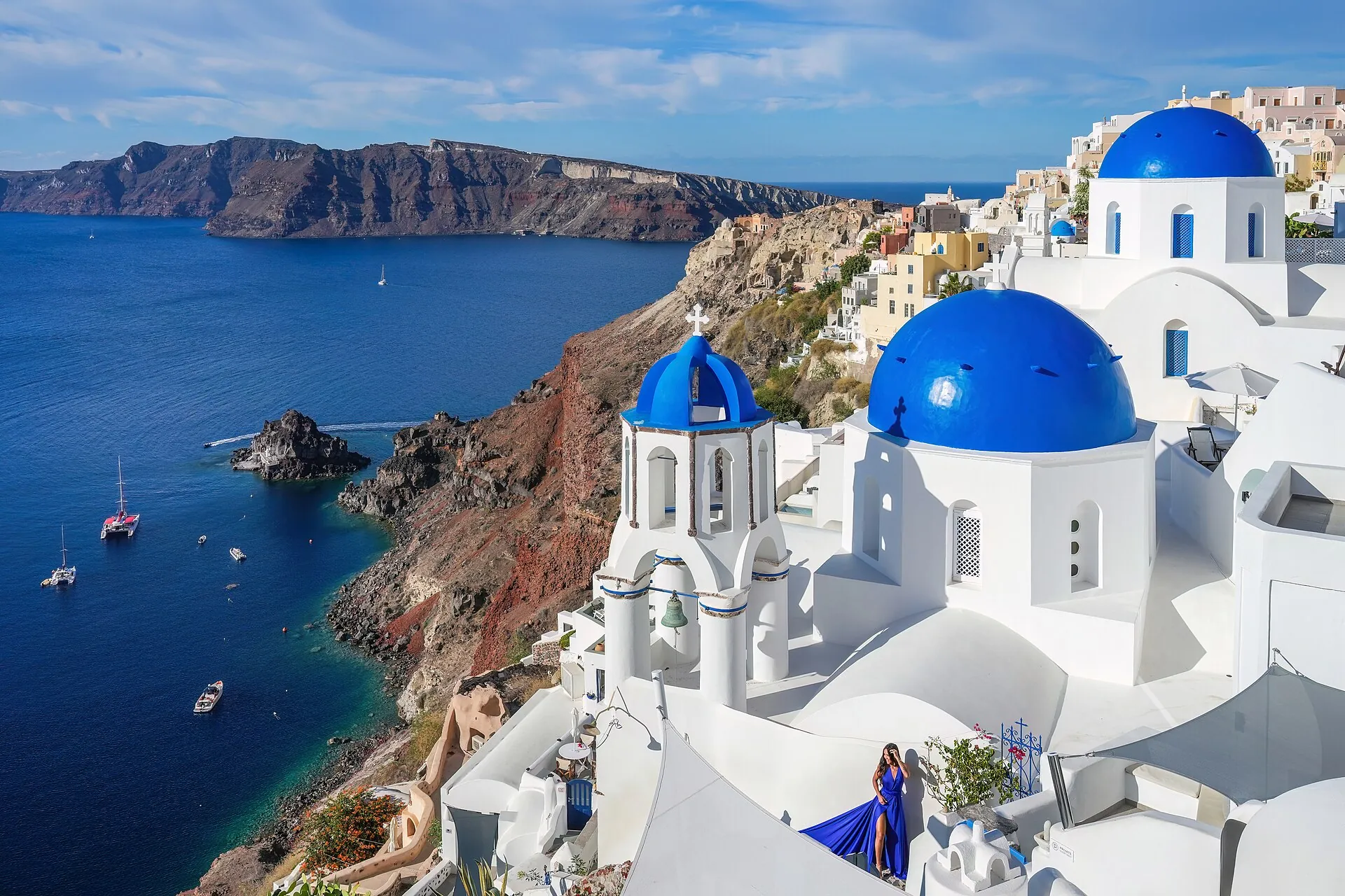 The blue domes of Oia above the caldera of Santorini, the deep blue sea and the island of Thirasia behind