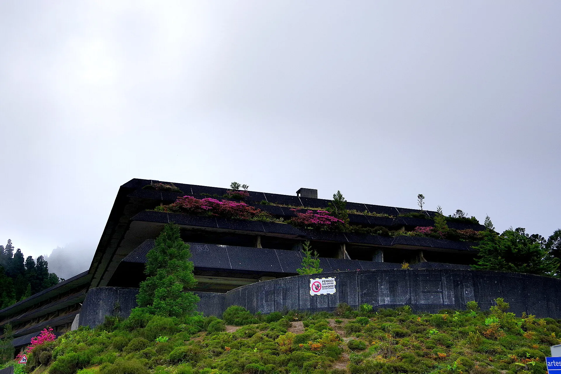 Die verfallene Hotelruine Monte Palace an der Vista do Rei in Sete Cidades, mit Zaun und Warnschild vor dem Eingang