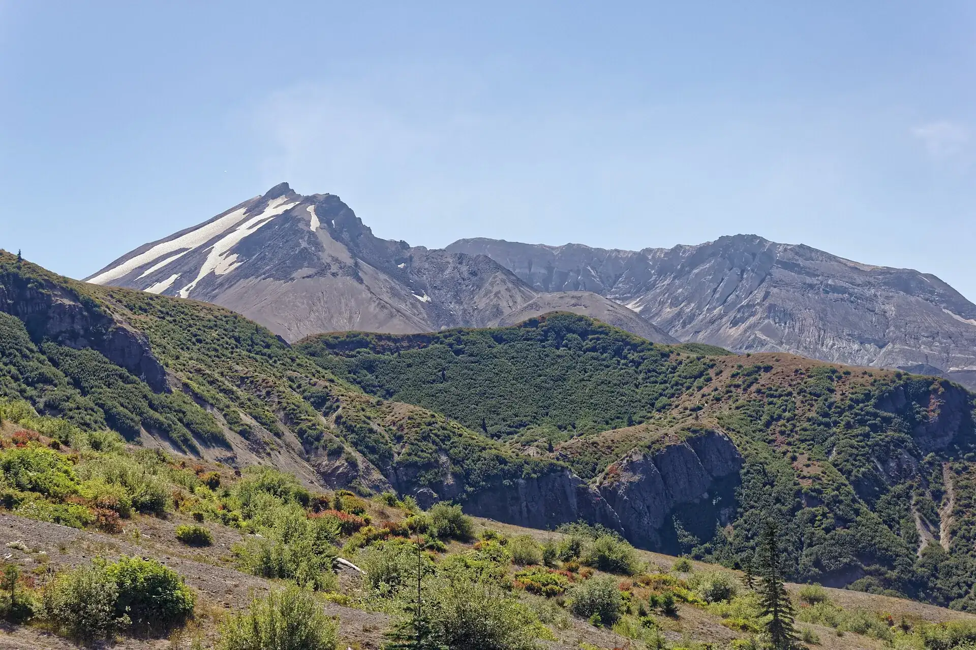 Der Krater des Mount St. Helens vom Windy Ridge aus: der offene Krater mit Dampffahne, davor bewaldete Rücken und graue Aschehänge