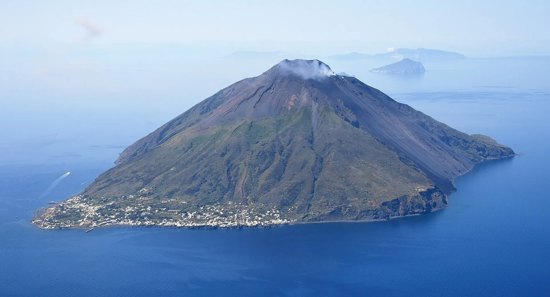 Aerial view of Stromboli from the north-east: the cone with a steam plume, the white houses of the village at its foot, sea behind