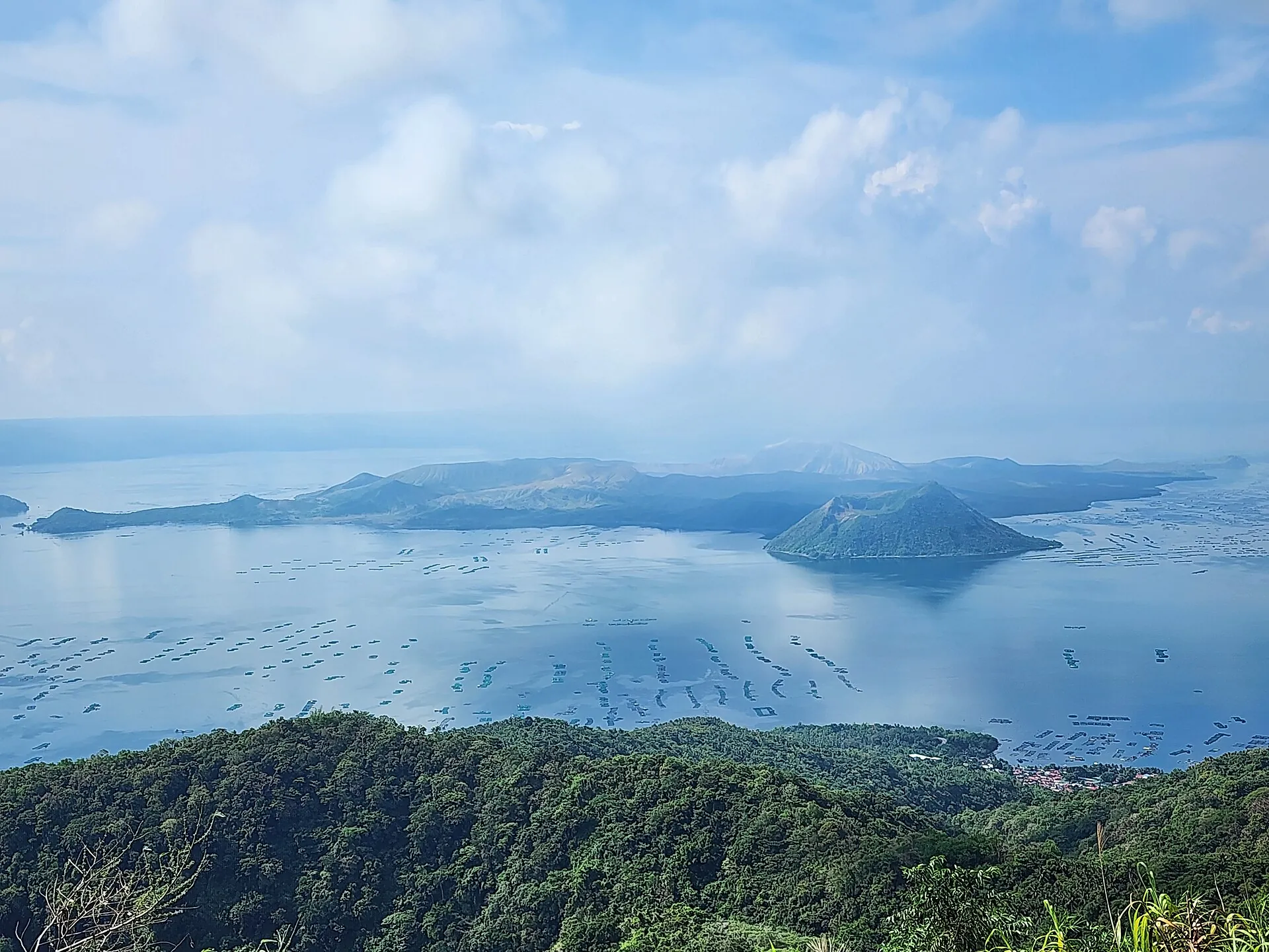 Die Vulkaninsel im Taalsee im Juni 2024 vom Calderarand bei Tagaytay aus, die Hänge wieder grün, Fischgehege auf dem Wasser