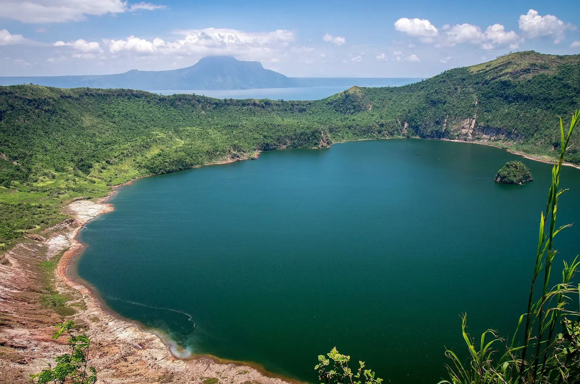 Der Kratersee im Hauptkrater des Taal im Jahr 2014, grünes Wasser, darin die kleine Felsinsel Vulcan Point, dahinter der Taalsee