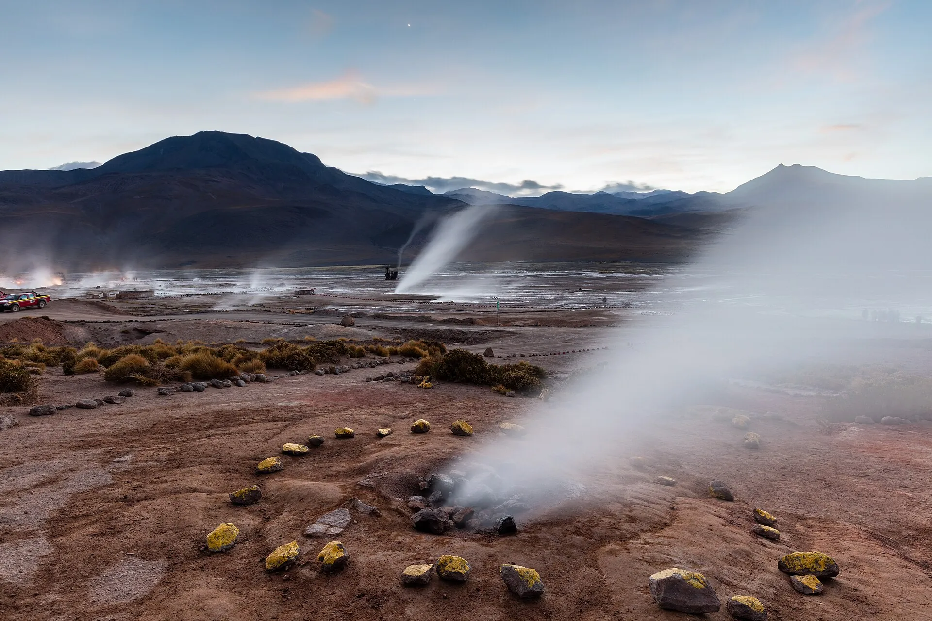 A geyser erupting at El Tatio in the first morning light, the mountains of the Altiplano behind