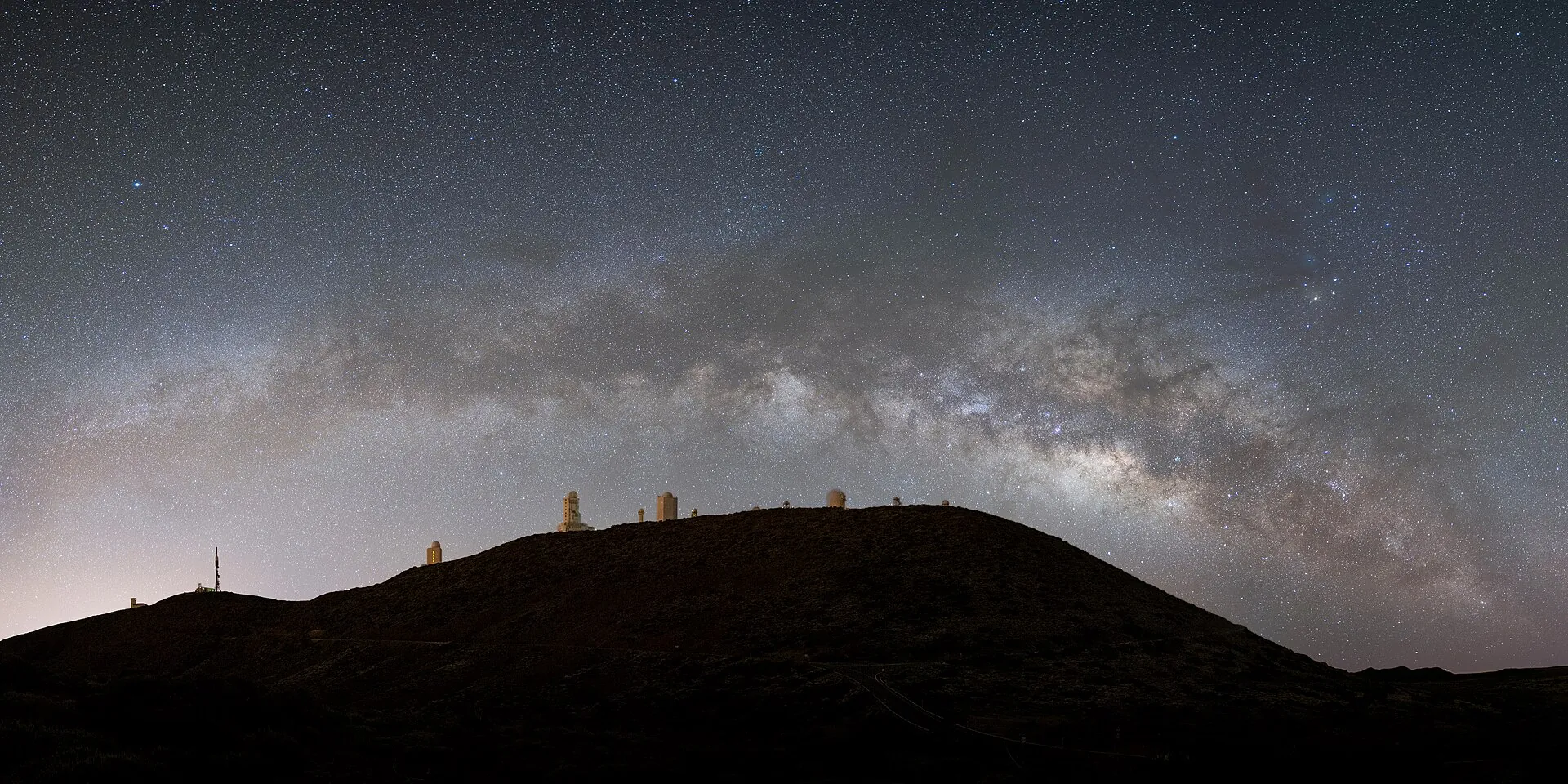 The Milky Way above the ridge of the Izaña observatory, the domes as silhouettes against the starry sky