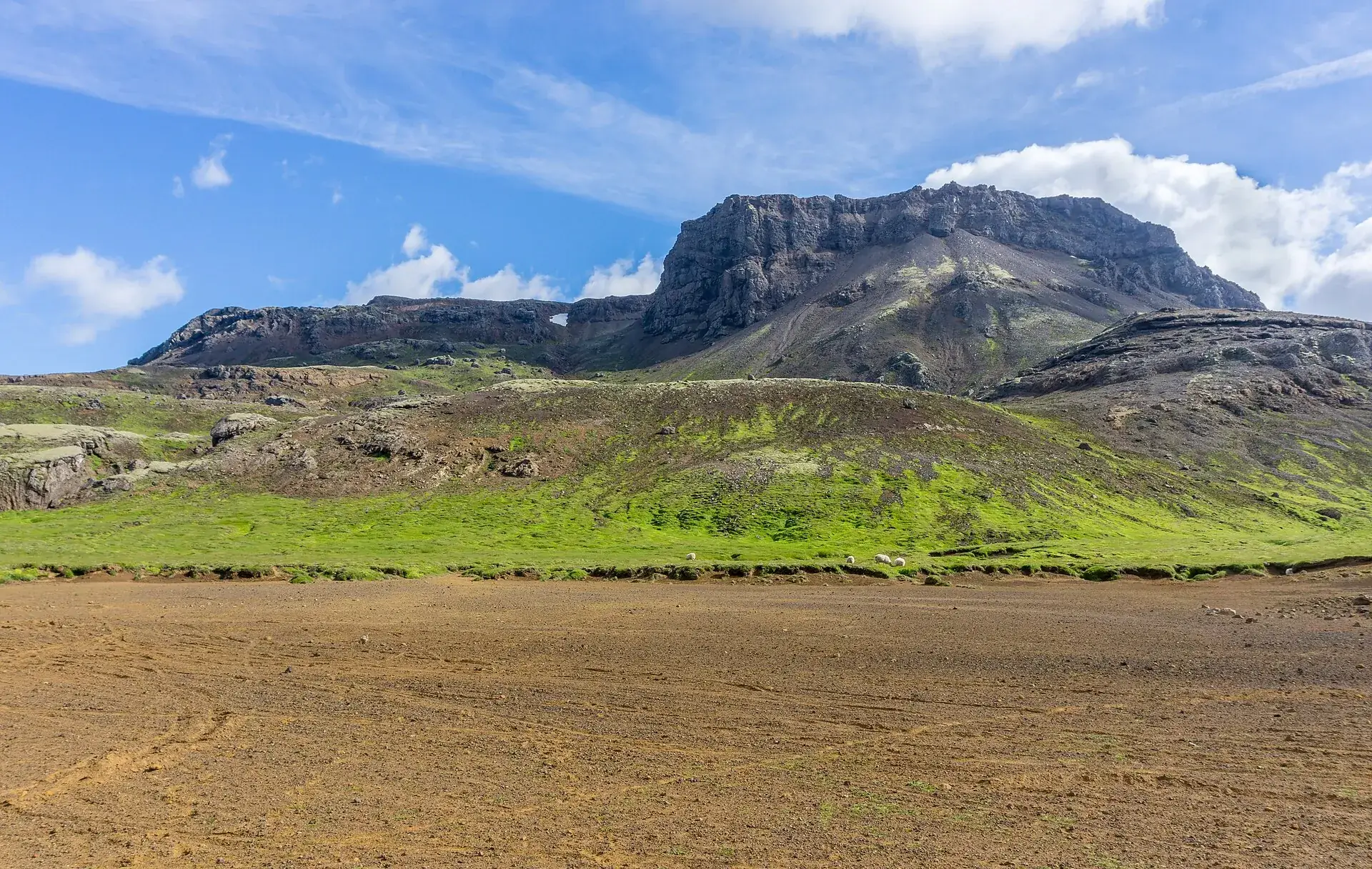 Ein Tafelberg in den Bláfjöll über einer Ebene aus Lavasand und Moos, blauer Himmel mit Wolken